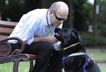 Rolf seated and leans over affectionately to Seeing Eye Dog Echo